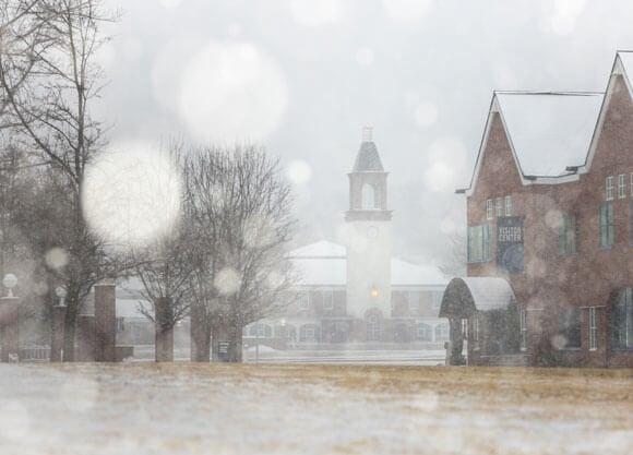 Snow falls on the Mount Carmel Campus with Arnold Bernhard Library in the background.