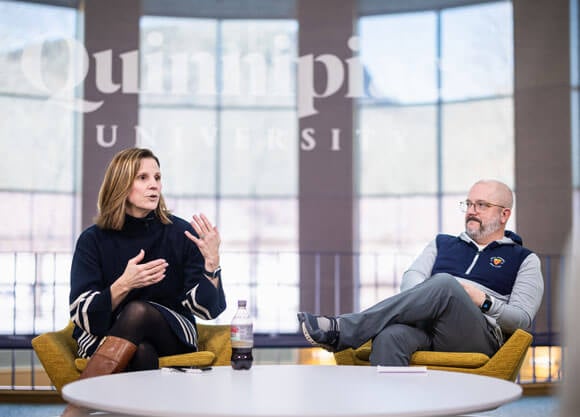 Two individuals sit and talk to each other in the open air studio on the Mount Carmel Campus.