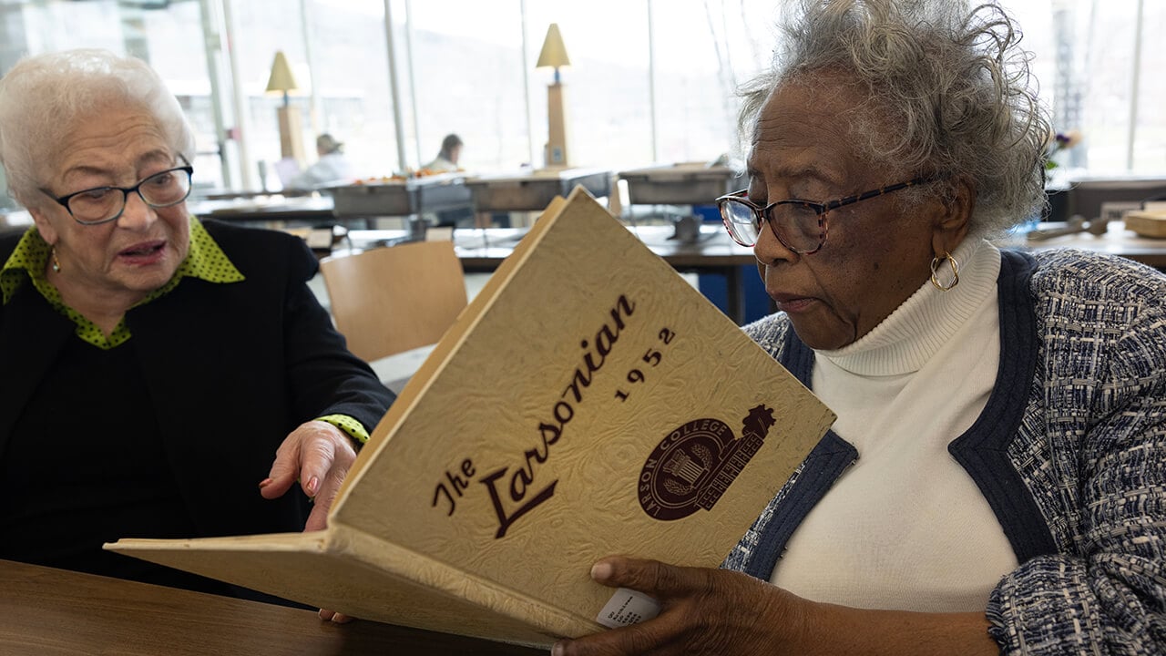 Larson alumnae look at a yearbook.