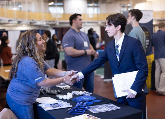 Student shakes employers hand at the career fair.