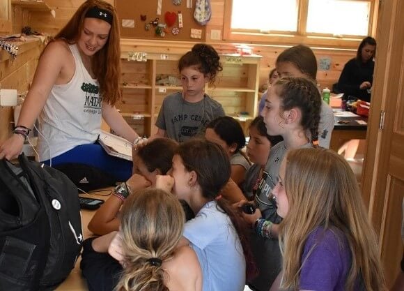 Female student surrounded by 8 young girls, all looking at computer screen