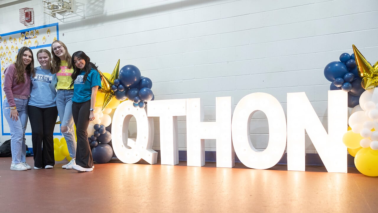 Girls posing with the QTHON sign