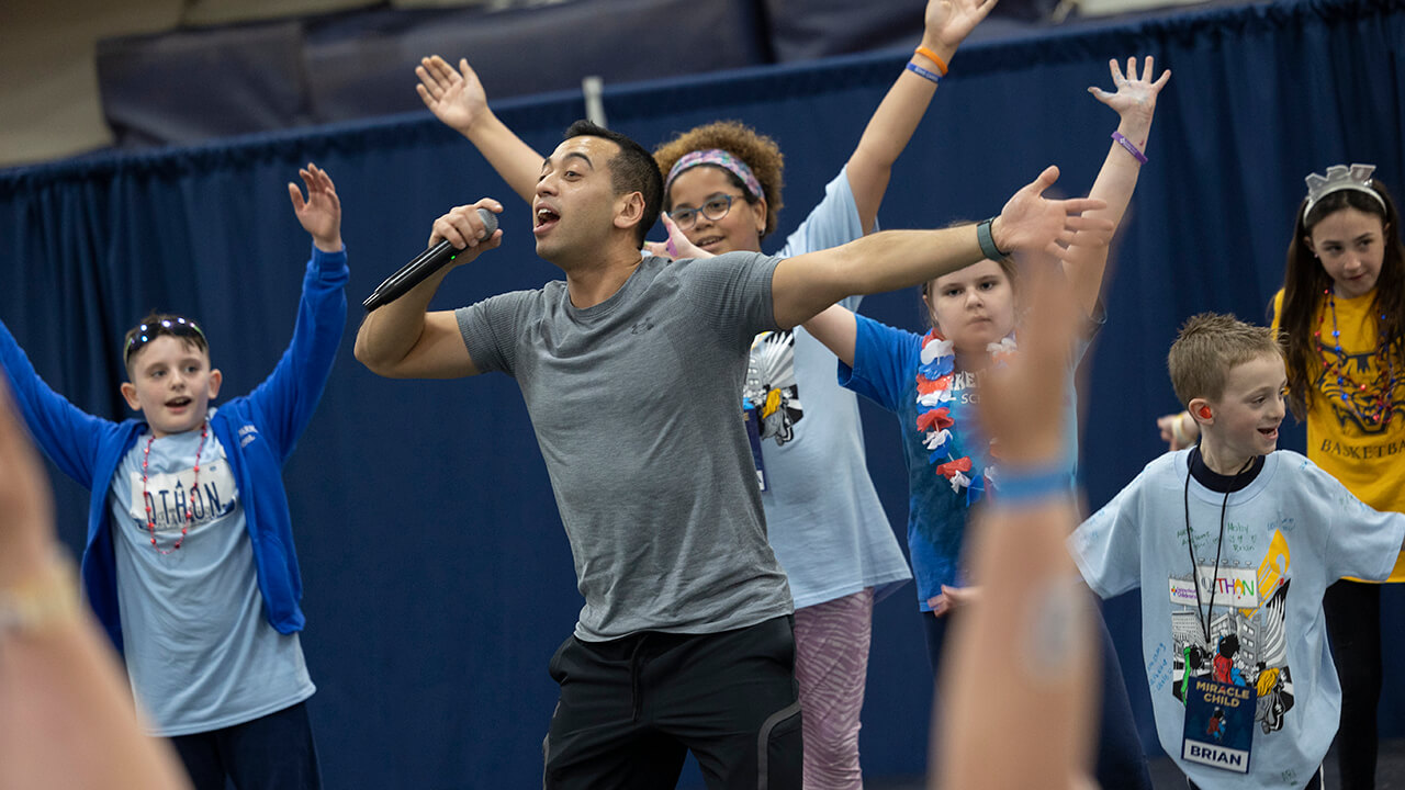 Children dancing on stage with QTHON performer