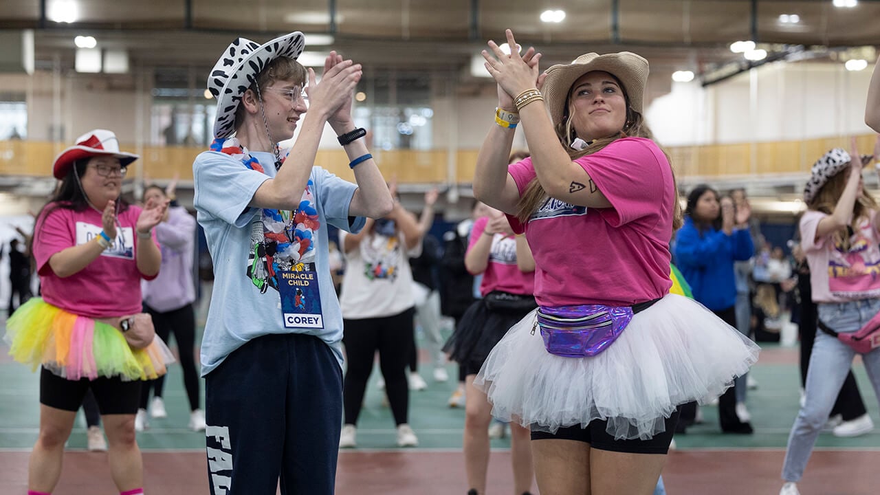 Two students dance in cowboy hats while clapping