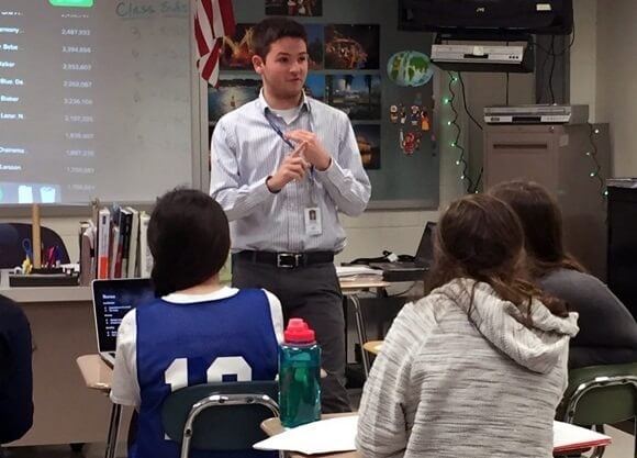 Graduate student teaches in front of a room of school-age students