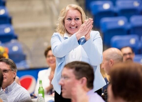 Female employee standing up and clapping in a crowd