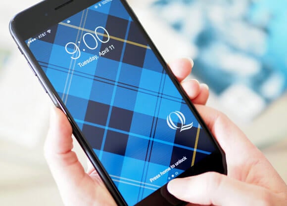 Hand holding an iPhone with Quinnipiac Plaid background wallpaper