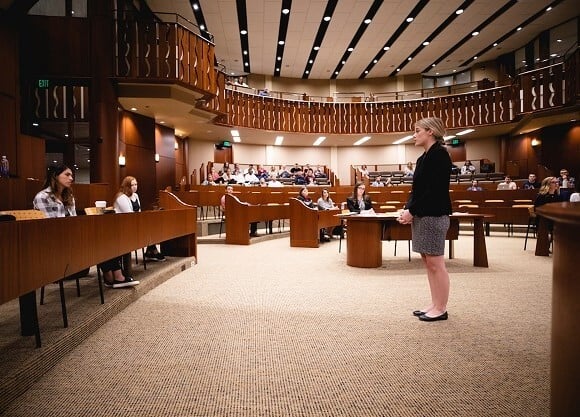 Laura Hamilton stands in Quinnipiac's ceremonial courtroom speaking to an audience of fellow students