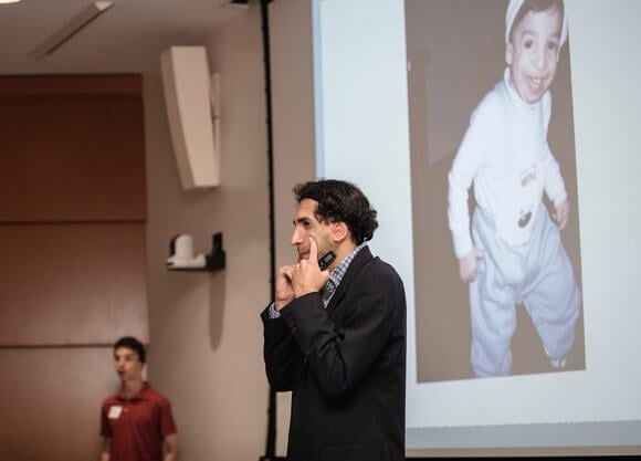 A man with Treacher Collins Syndrome speaks to an auditorium of people