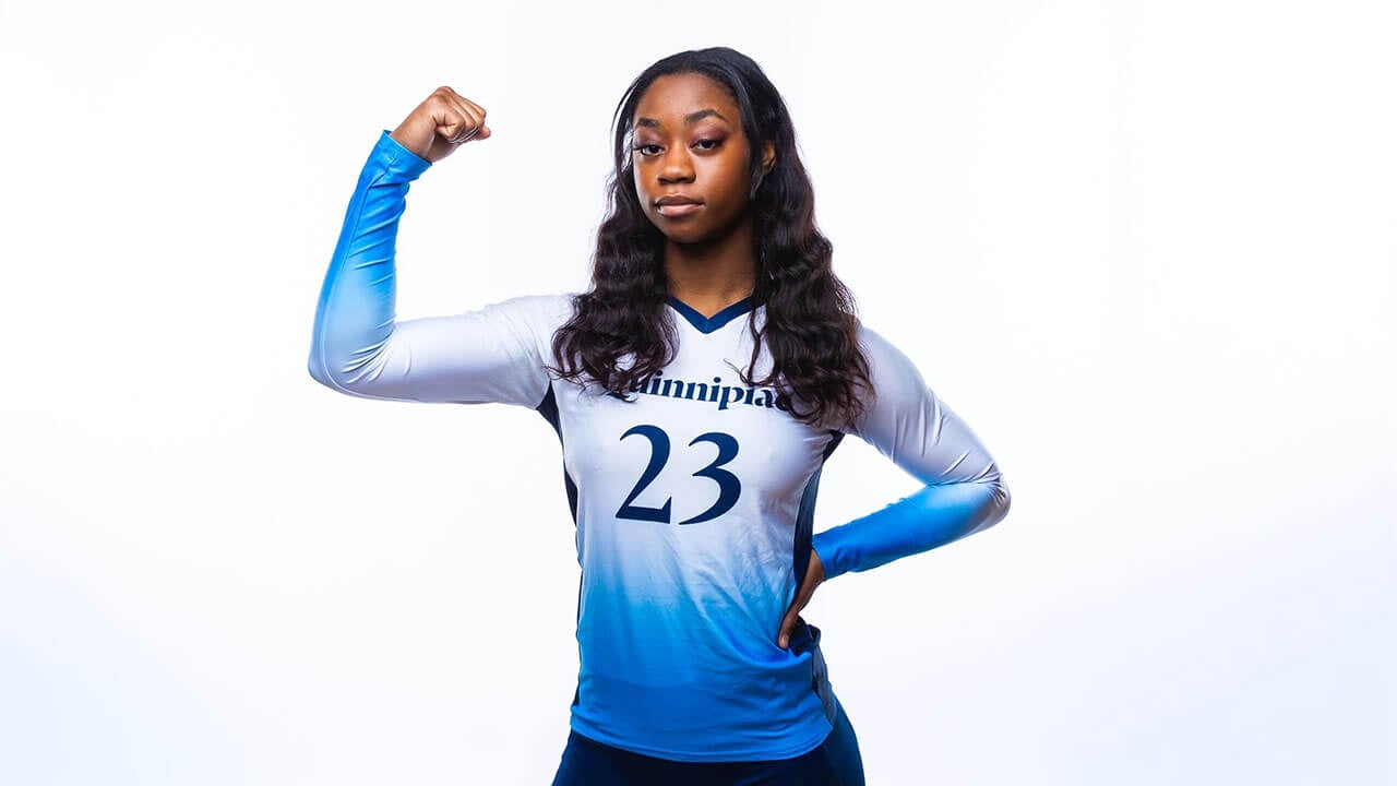 bri marks poses with one hand on her hip and one arm flexing in a closed fist. she has dark wavy hair