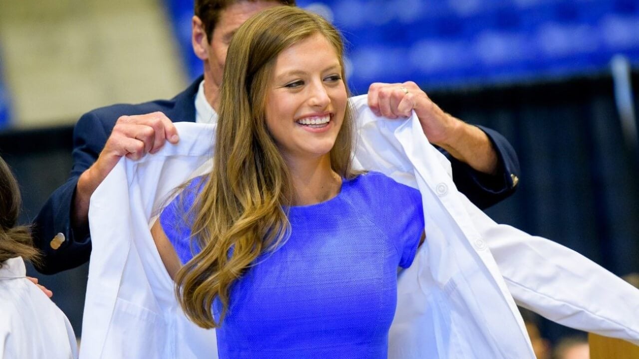 Student receives her coat from a professor during the medical school's White Coat Ceremony