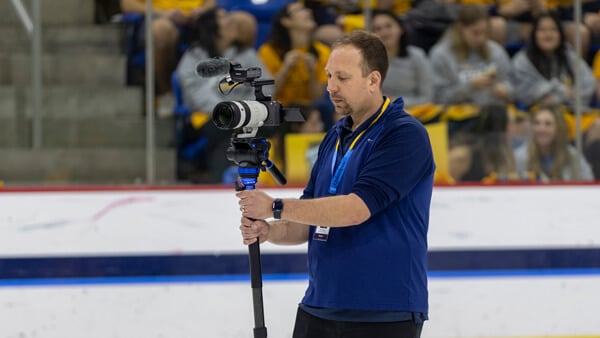 A man holding a camera in a hockey rink
