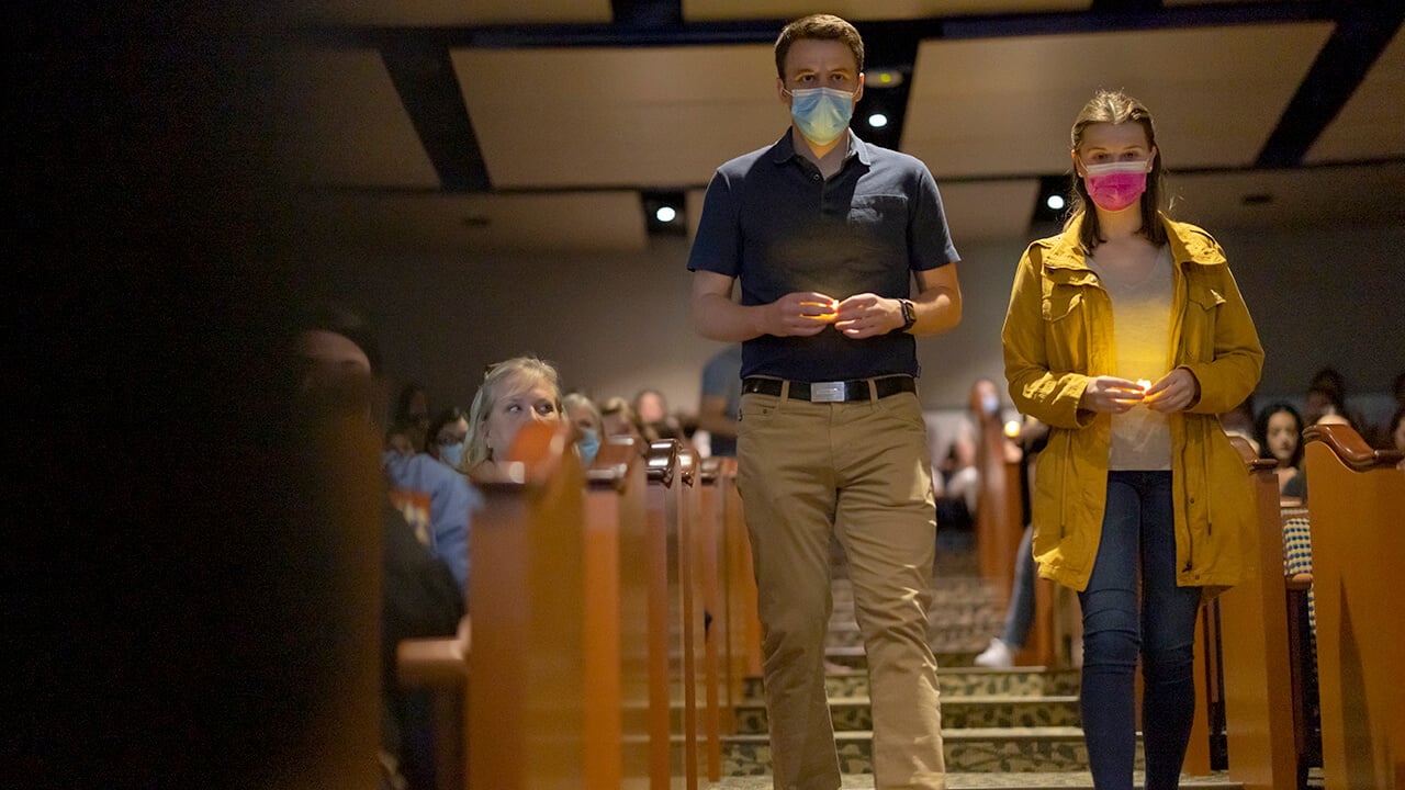 Two students carry candles down steps at the gratitude ceremony