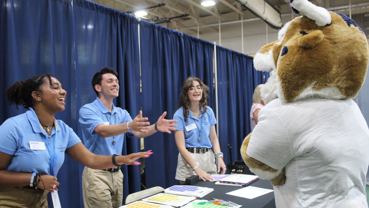 Quinnipiac Orientation Leaders extend their arms out towards Boomer
