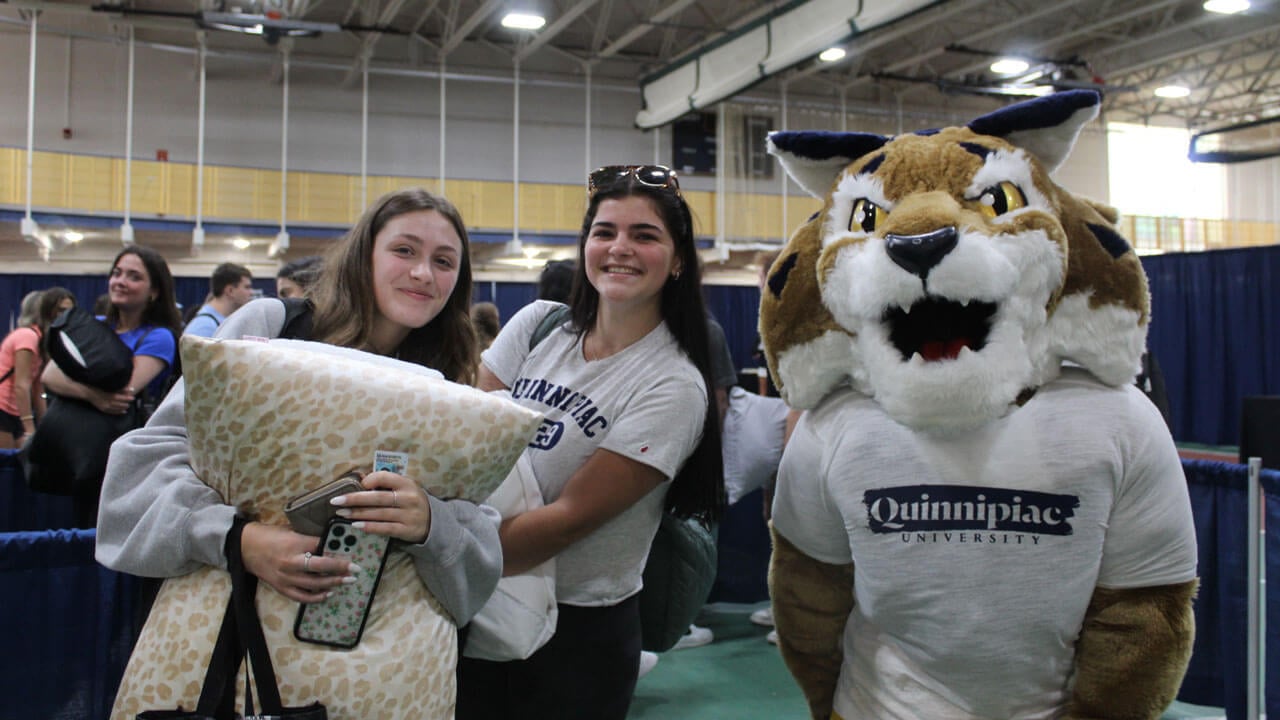 Quinnipiac orientation students holding their luggage smiling with Boomer