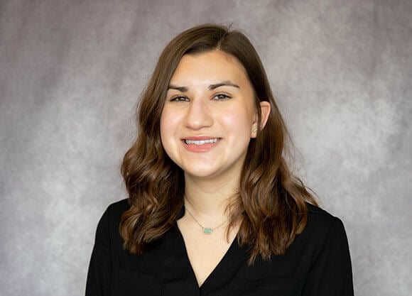 Jacqueline Ydrovo in a black shirt smiling with a grey background