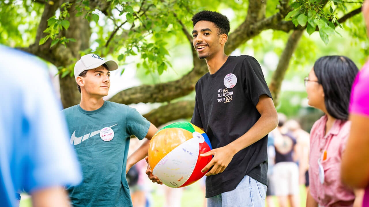 First-year talking and holding a beach ball  for game Orientation activity