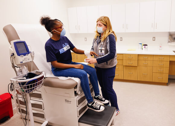 A Hartford HealthCare nurse applies a bandage to a Quinnipiac student's hand in an exam room
