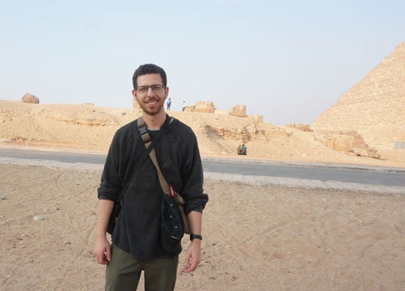Peter O'Neill standing in front of a desert and pyramids