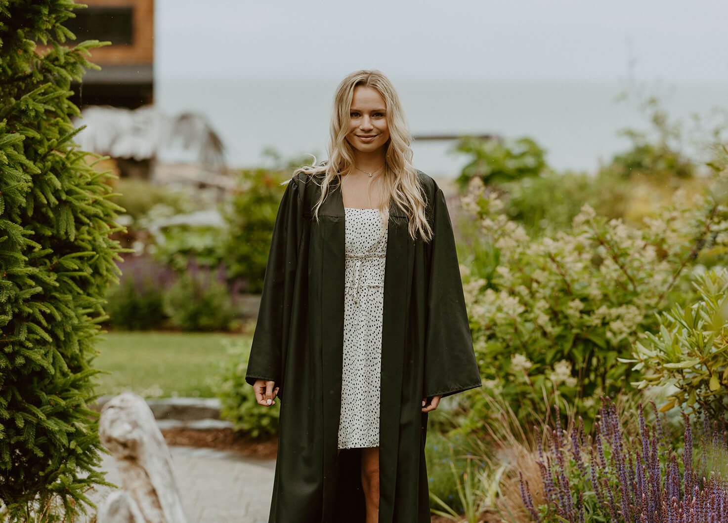 Alumna Mckenna Haz posing in her academic regalia