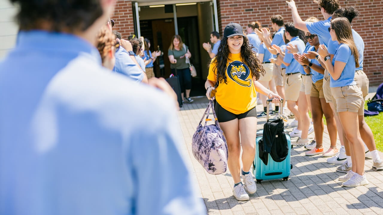 Student carries luggage as they walk outside
