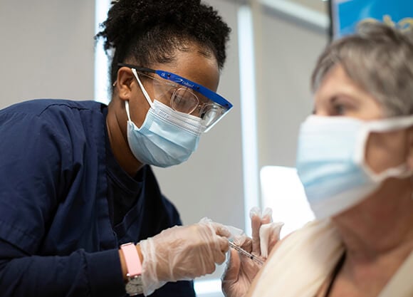 Student administers the COVID-19 vaccine to a female patient