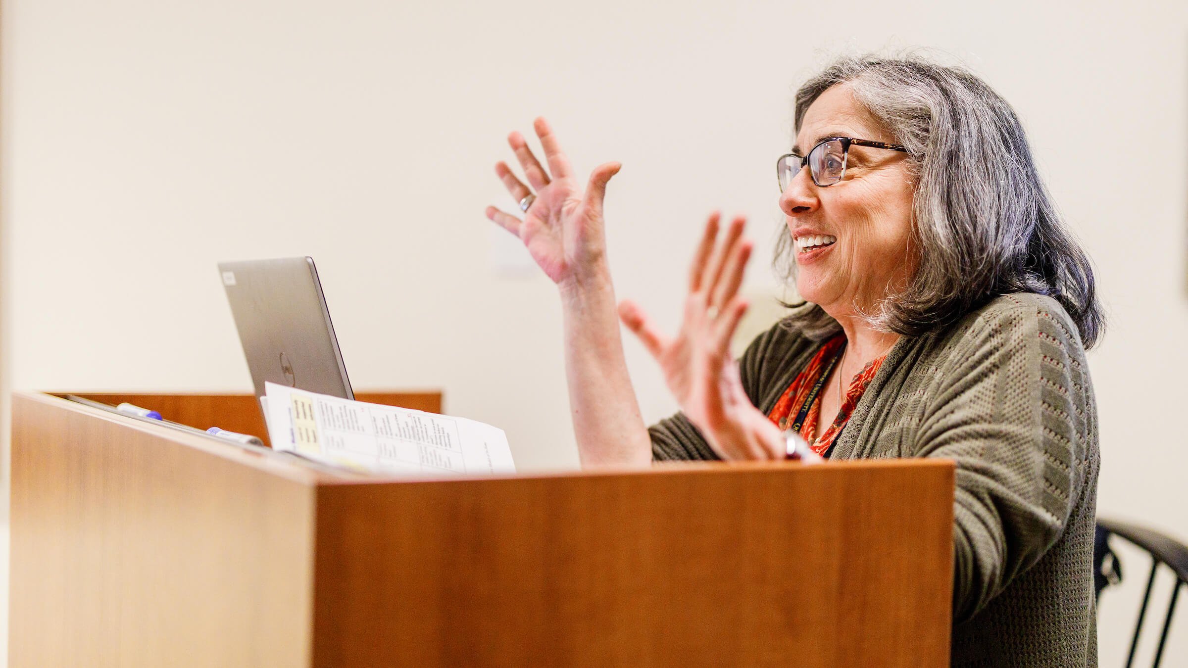 Faculty member Laura Mutrie behind a podium talking