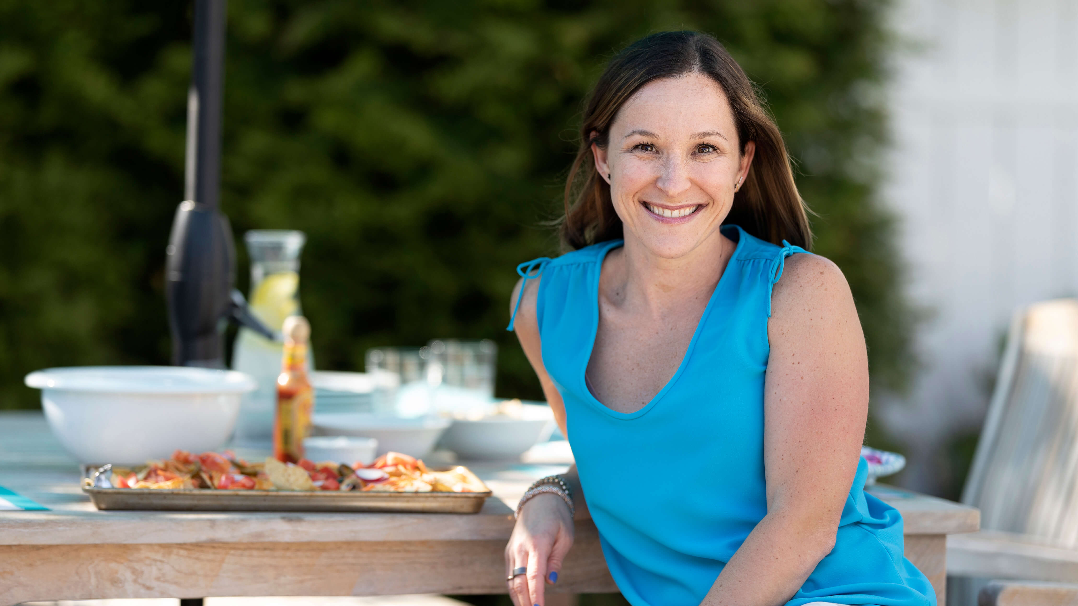 Professor Dana White posing on a picnic bench with food in the background