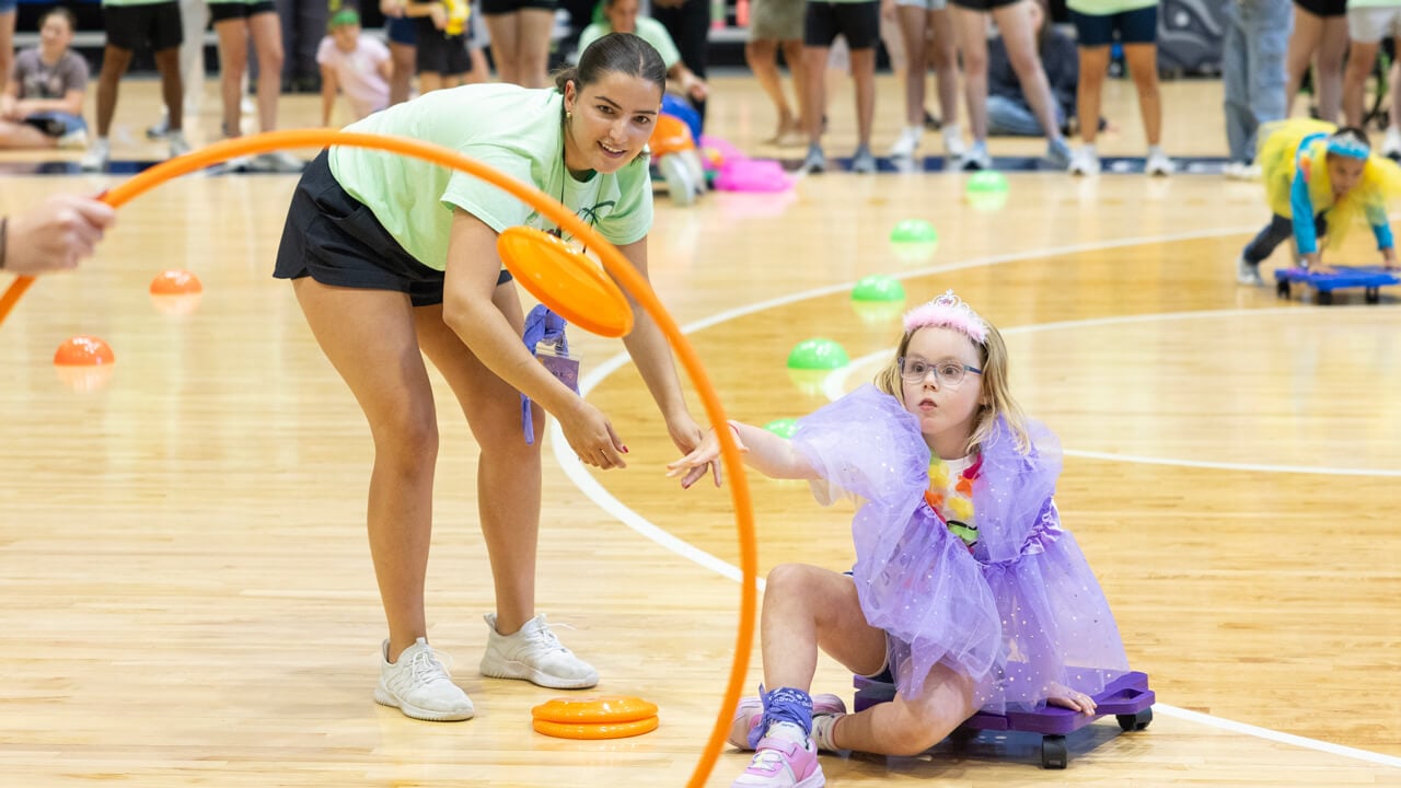 A young girl throws a frisbee through a hula hoop