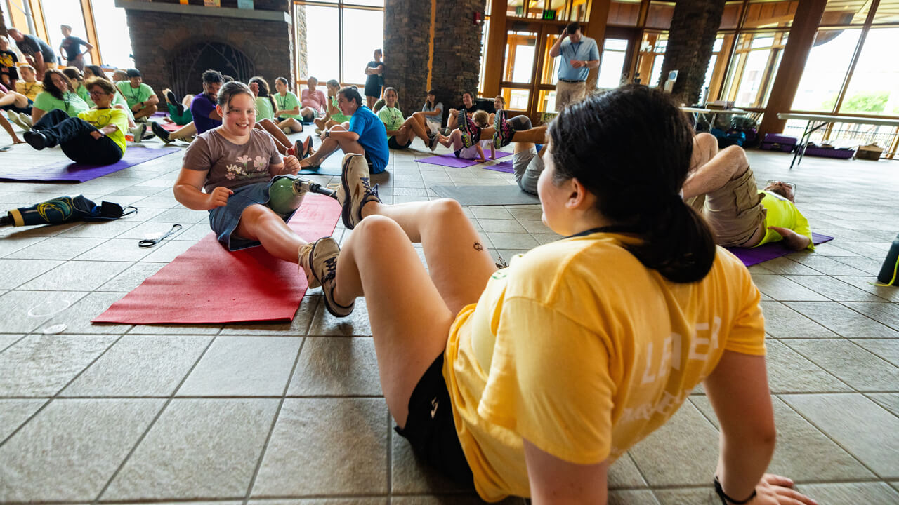 Volunteer and participants work on yoga mat together