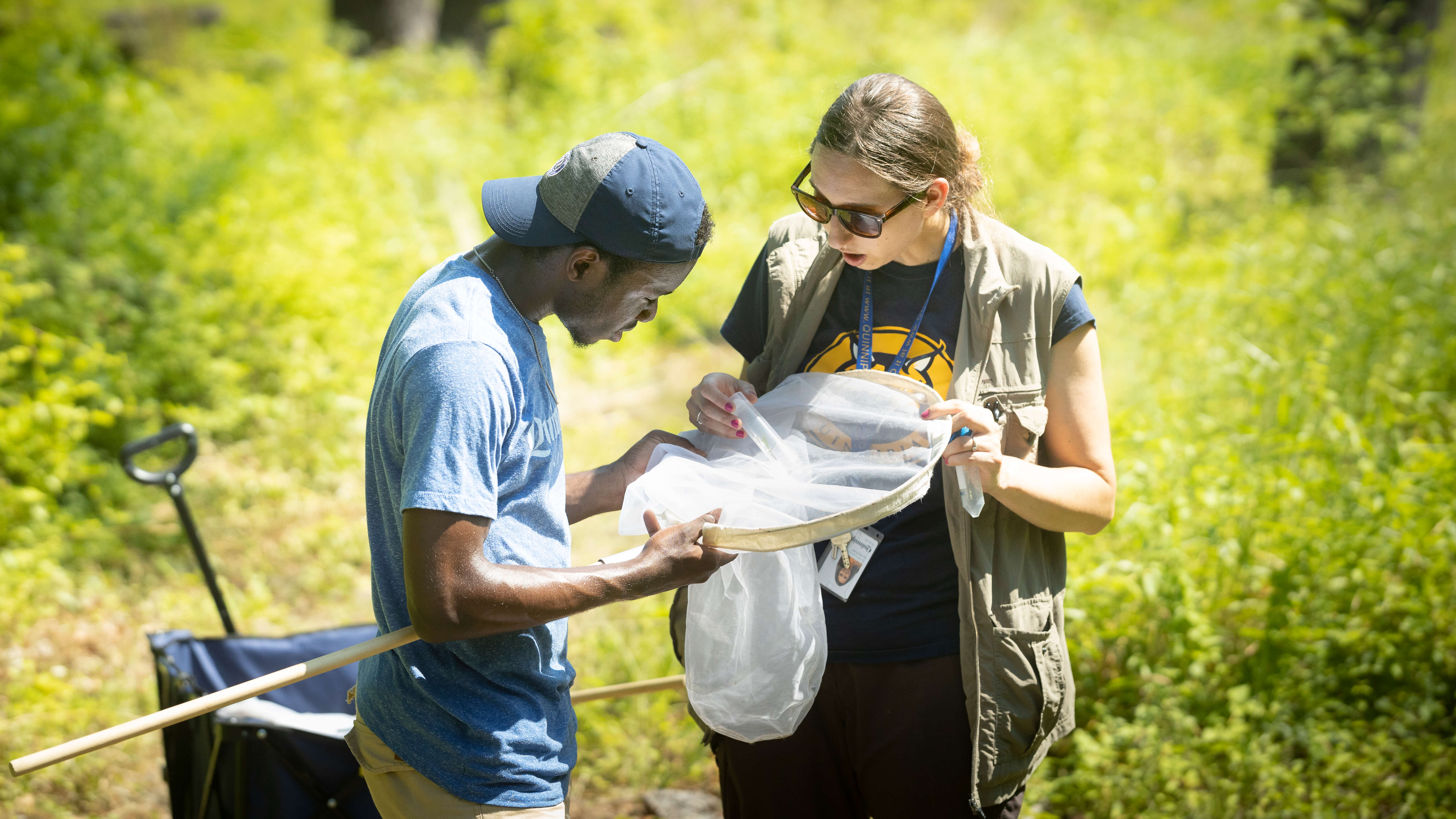 Sarah Lawson and student stand in field with net studying a bee they caught