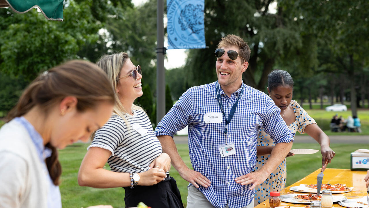 Two students laughing by the food table on the lawn