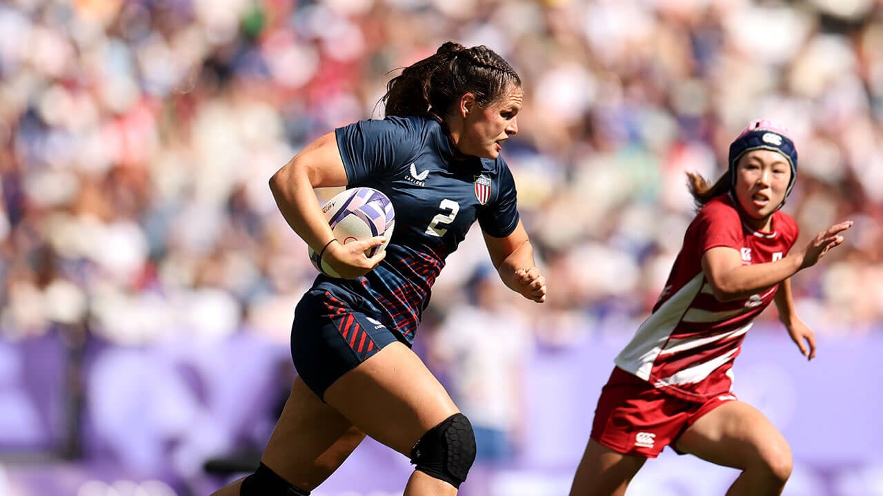 Ilona Maher runs with the rugby ball under her arm against a Japanese player in the 2024 Olympics