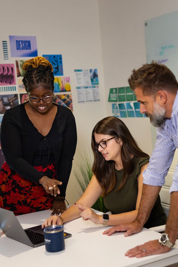 2 women and a man looking at a laptop screen