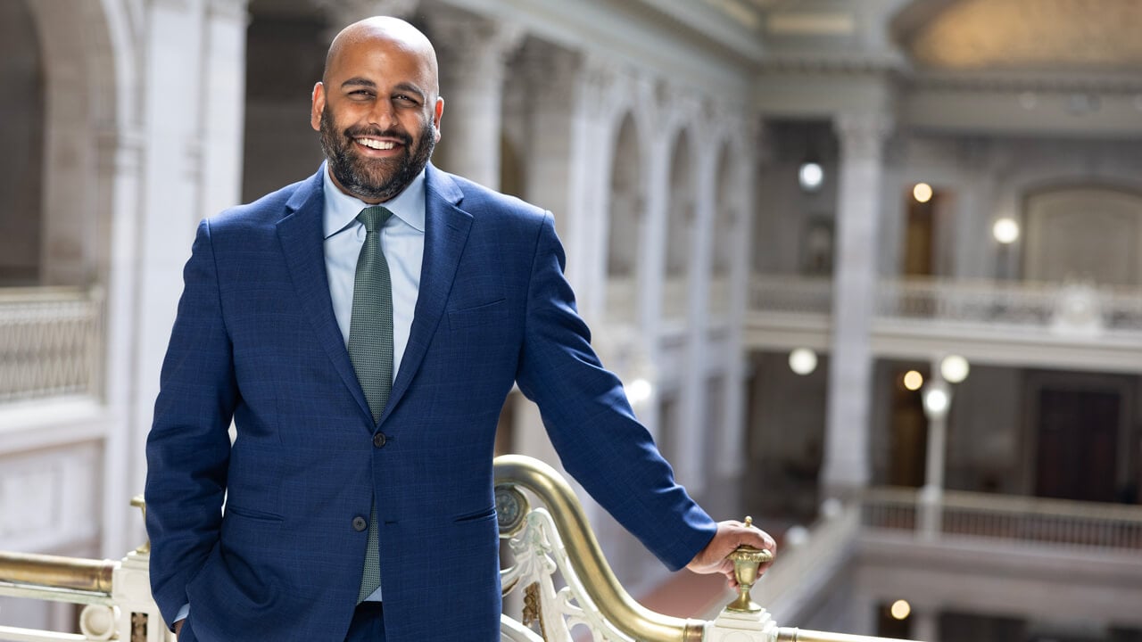 Arunan Arulampalam smiles for a photo from a balcony in the Hartford City Hall