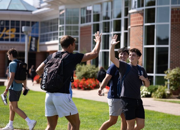 Students give each other a high five in front of the Carl Hansen Student Center