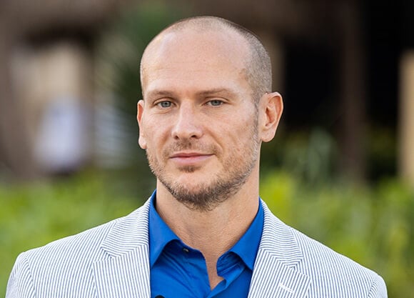 A photo of Quinnipiac professor Dave DesRoches wearing a blue shirt and gray blazer.