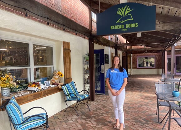 Kelsey Fallon standing under an overhead sign for ReRead Books and More store