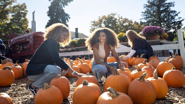 Two students smiling while pumpkin picking