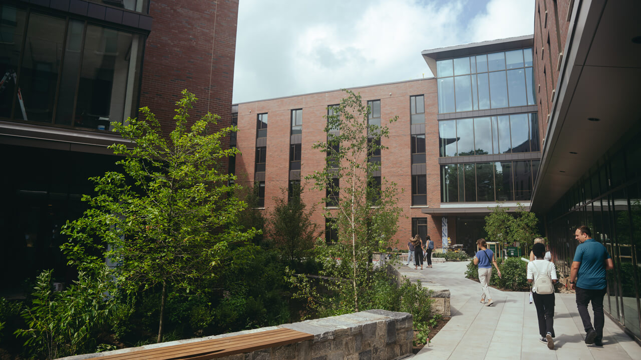 A half dozen people walk through the newly constructed courtyard outside The Grove residence hall