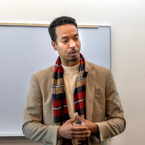 John Wood Jr. stands and speaks with his hands clasped in front of him