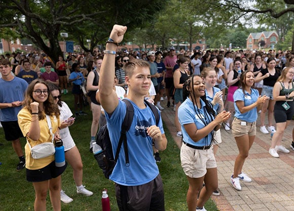 Students rally together cheering and raising their hands