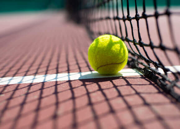 A tennis ball on a line on a tennis court