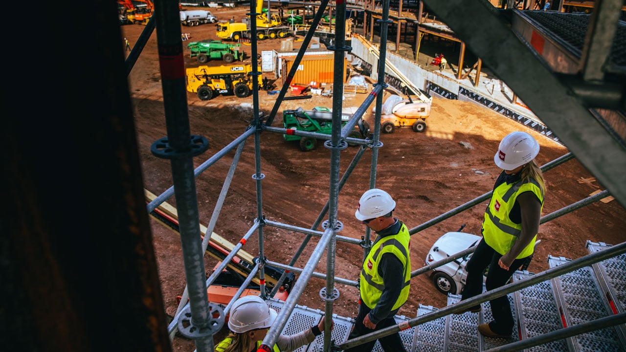 Construction workers walk down the stairs of the site.