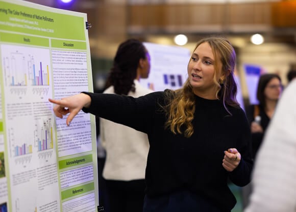 Biology major Louise Bacon explains her research at annual Exploratorium.