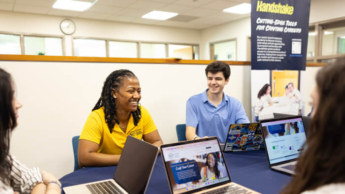 Faculty and students smile during a meeting in the Career Development Center.