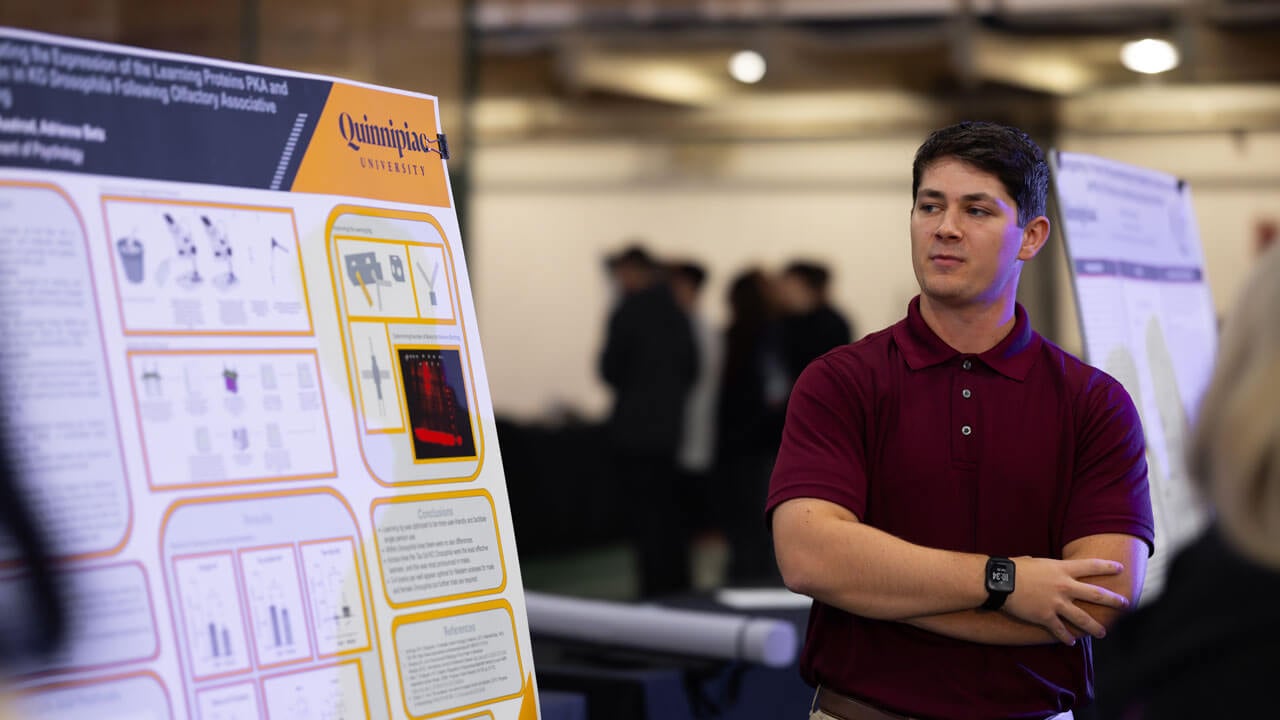 Student in a red button up shirt looks to his research with a stern look