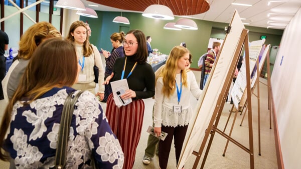 A student discussing her work with a group in front of her poster