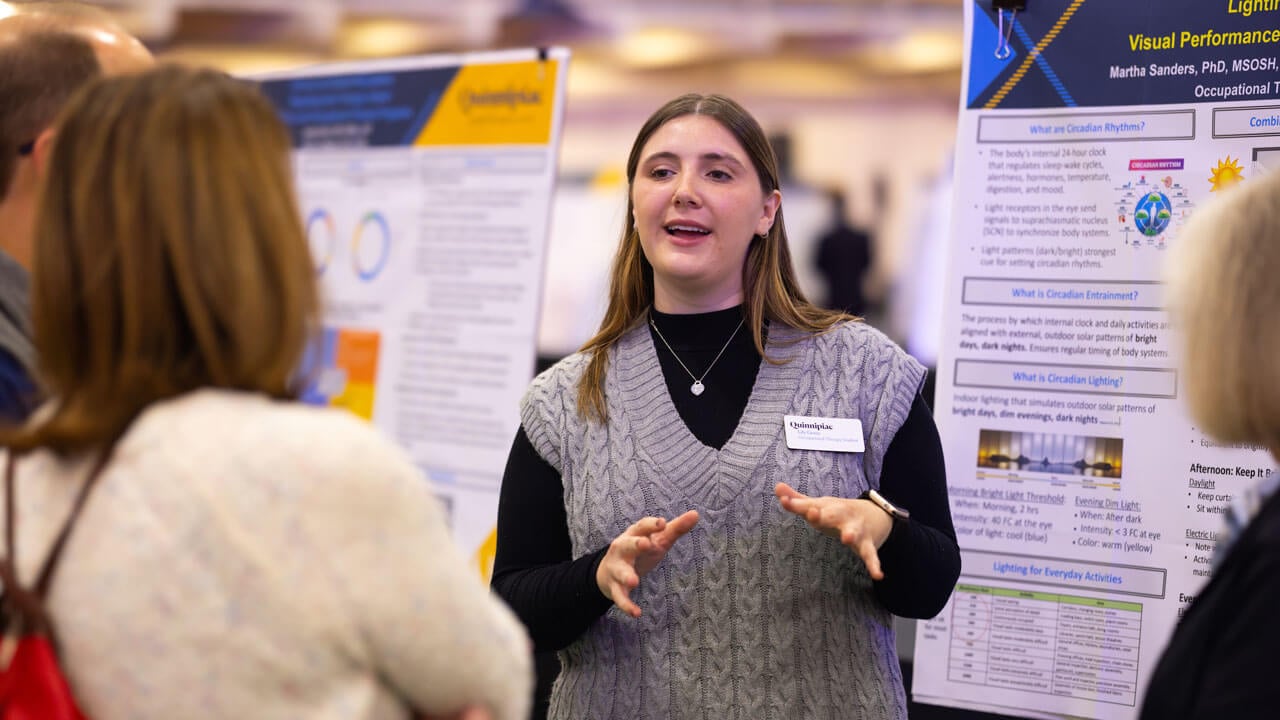 Student explains her research to a spectator while talking with her hands