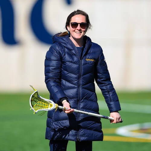 Photo of the Head Women's Lacrosse Coach, Jordan Christopher, holding a lacrosse stick.